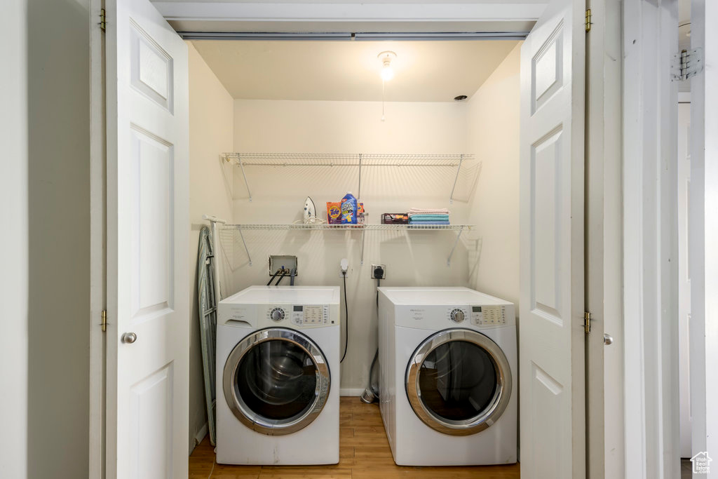 Clothes washing area featuring washer hookup, light hardwood / wood-style flooring, washer and clothes dryer, and hookup for an electric dryer