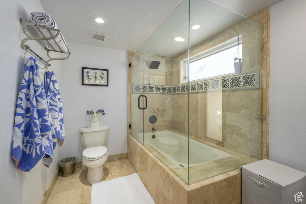 Bathroom with toilet, enclosed tub / shower combo, and tile floors