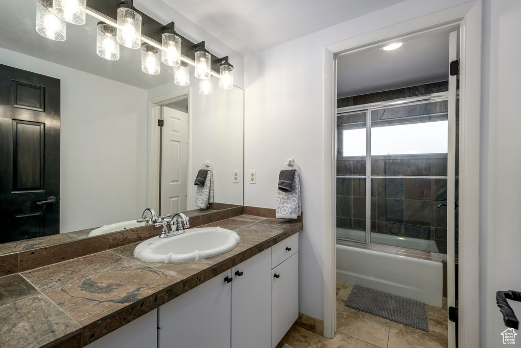 Bathroom featuring tile floors, vanity with extensive cabinet space, and shower / bath combination with glass door