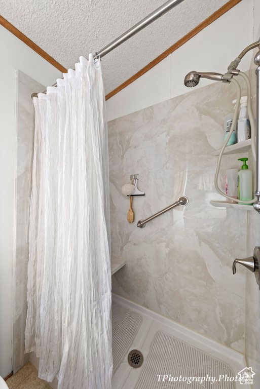 Bathroom with a shower with shower curtain, ornamental molding, a textured ceiling, and lofted ceiling