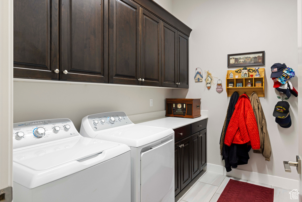 Laundry area with cabinets, washer and clothes dryer, and light tile floors