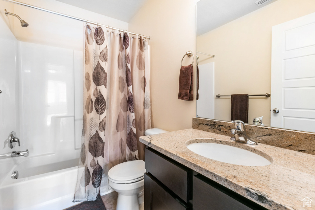 Full bathroom featuring shower / tub combo with curtain, toilet, and vanity with extensive cabinet space