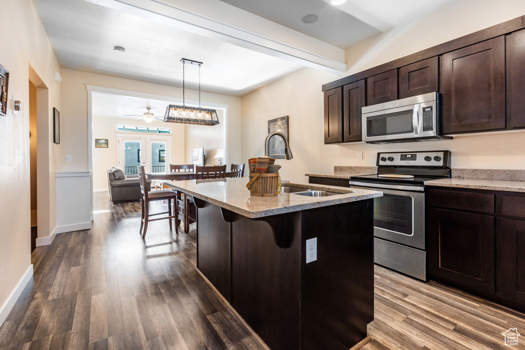Kitchen featuring french doors, ceiling fan with notable chandelier, hardwood / wood-style flooring, appliances with stainless steel finishes, and decorative light fixtures