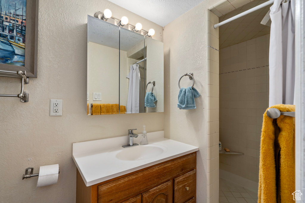 Bathroom featuring curtained shower, a textured ceiling, and vanity with extensive cabinet space