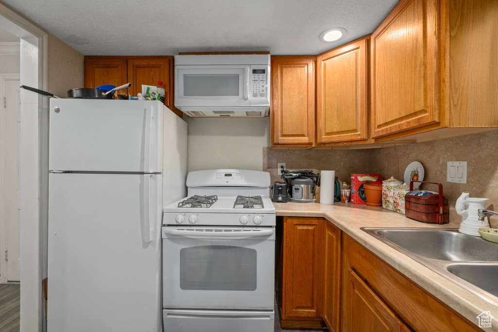 Kitchen with white appliances, tasteful backsplash, and sink