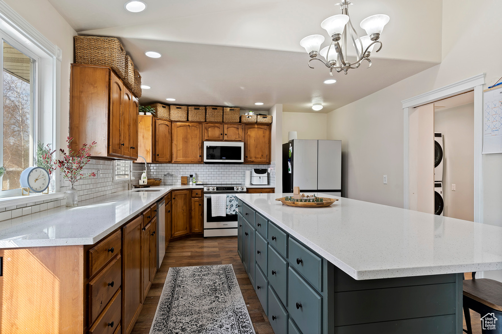 Kitchen featuring a notable chandelier, range, a center island, pendant lighting, and white refrigerator