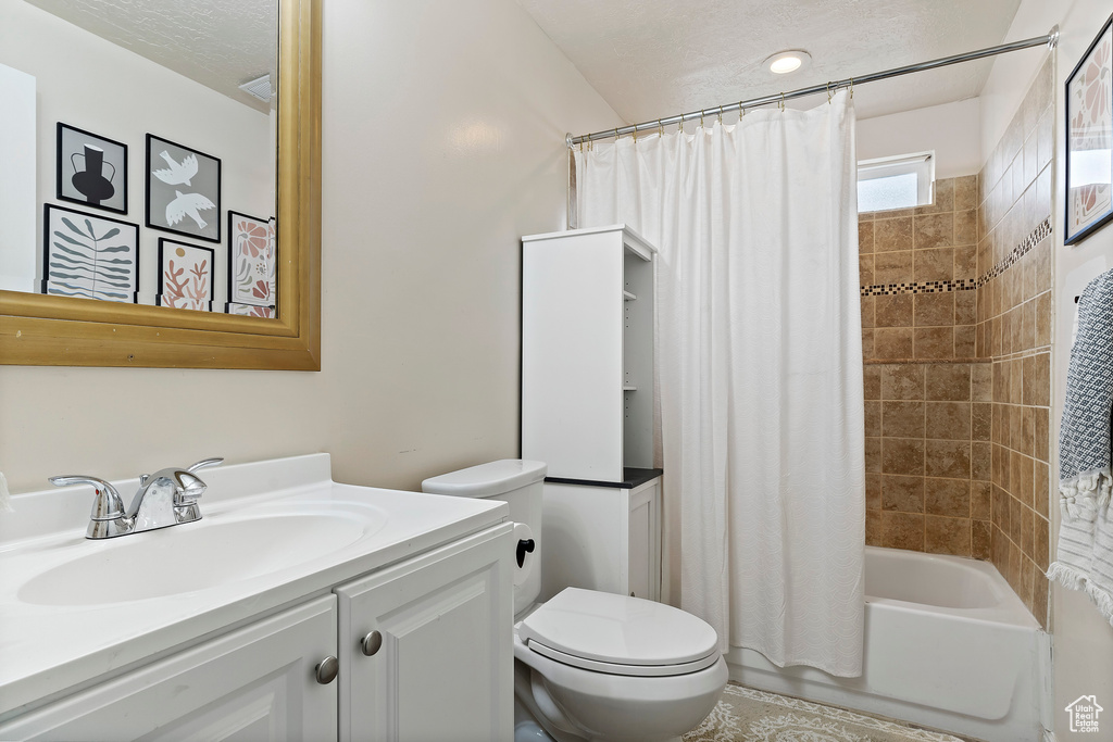 Full bathroom featuring vanity, toilet, a textured ceiling, and shower / tub combo