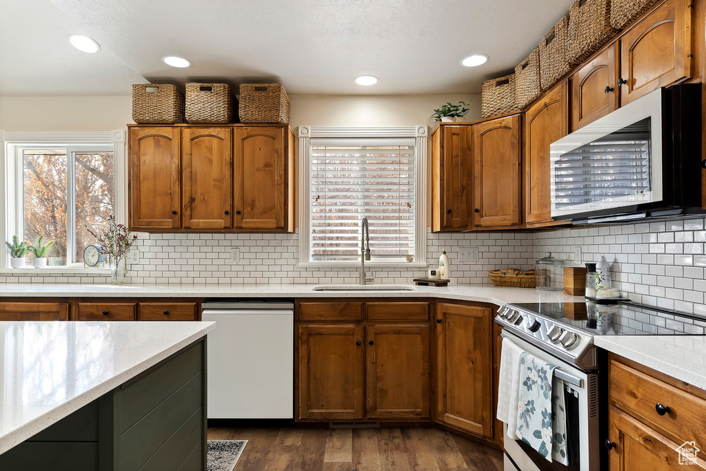 Kitchen featuring tasteful backsplash, electric range, sink, dark wood-type flooring, and white dishwasher