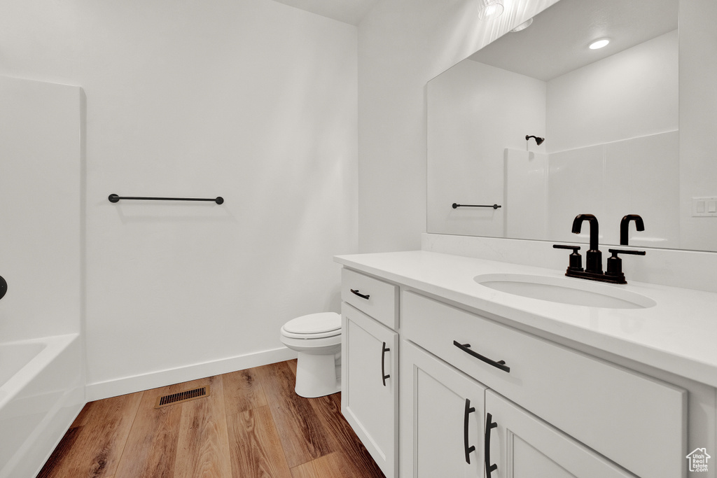 Full bathroom featuring vanity, toilet, wood-type flooring, and shower / bathtub combination