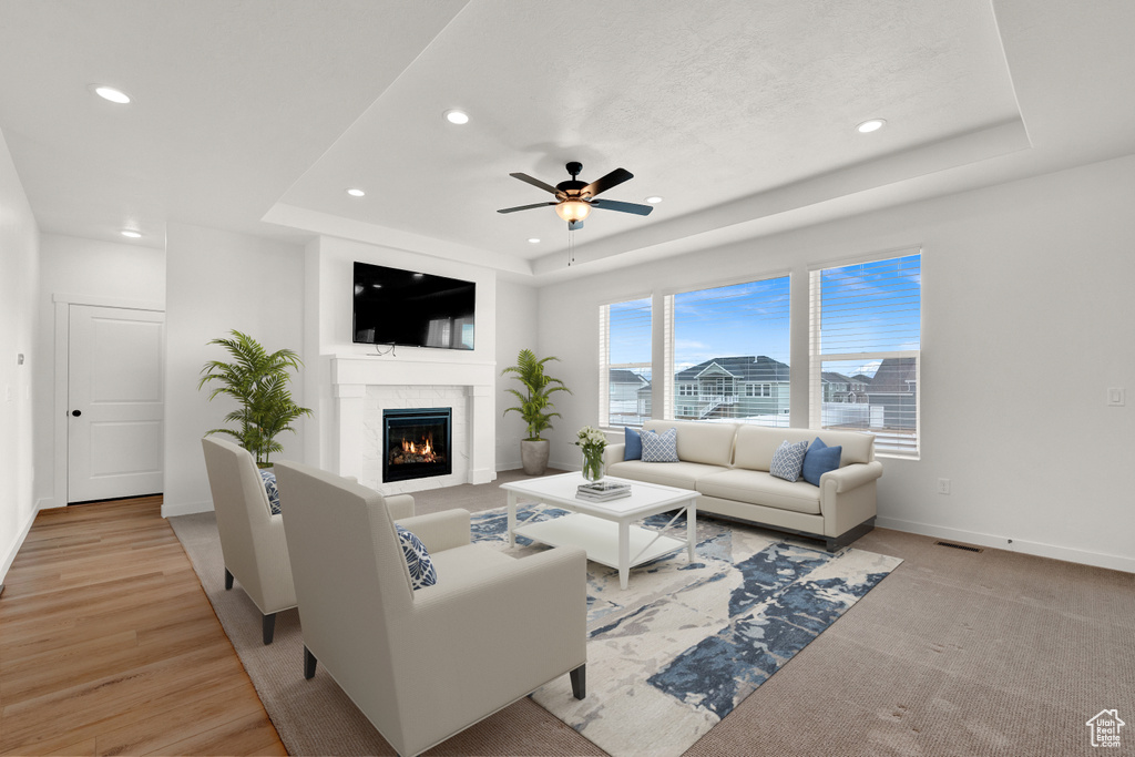 Living room featuring a tray ceiling, light wood-type flooring, and ceiling fan