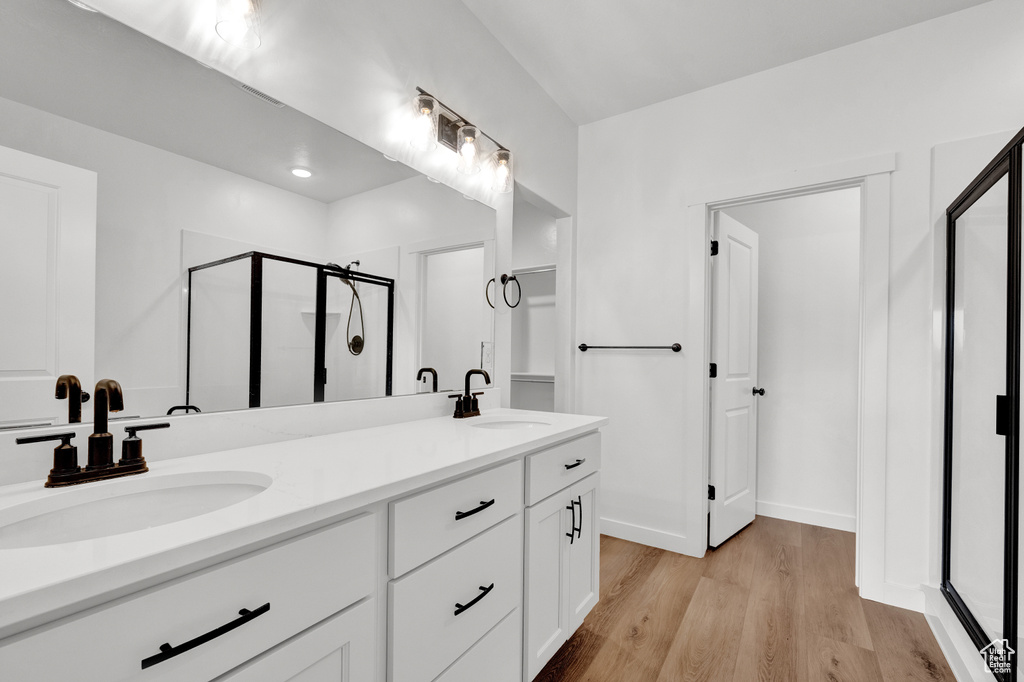 Bathroom with an enclosed shower, oversized vanity, hardwood / wood-style flooring, and double sink