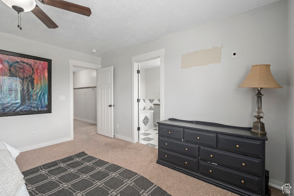 Carpeted bedroom featuring connected bathroom, a textured ceiling, and ceiling fan