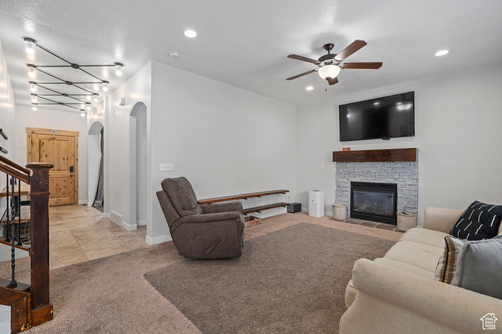 Carpeted living room with ceiling fan with notable chandelier and a fireplace