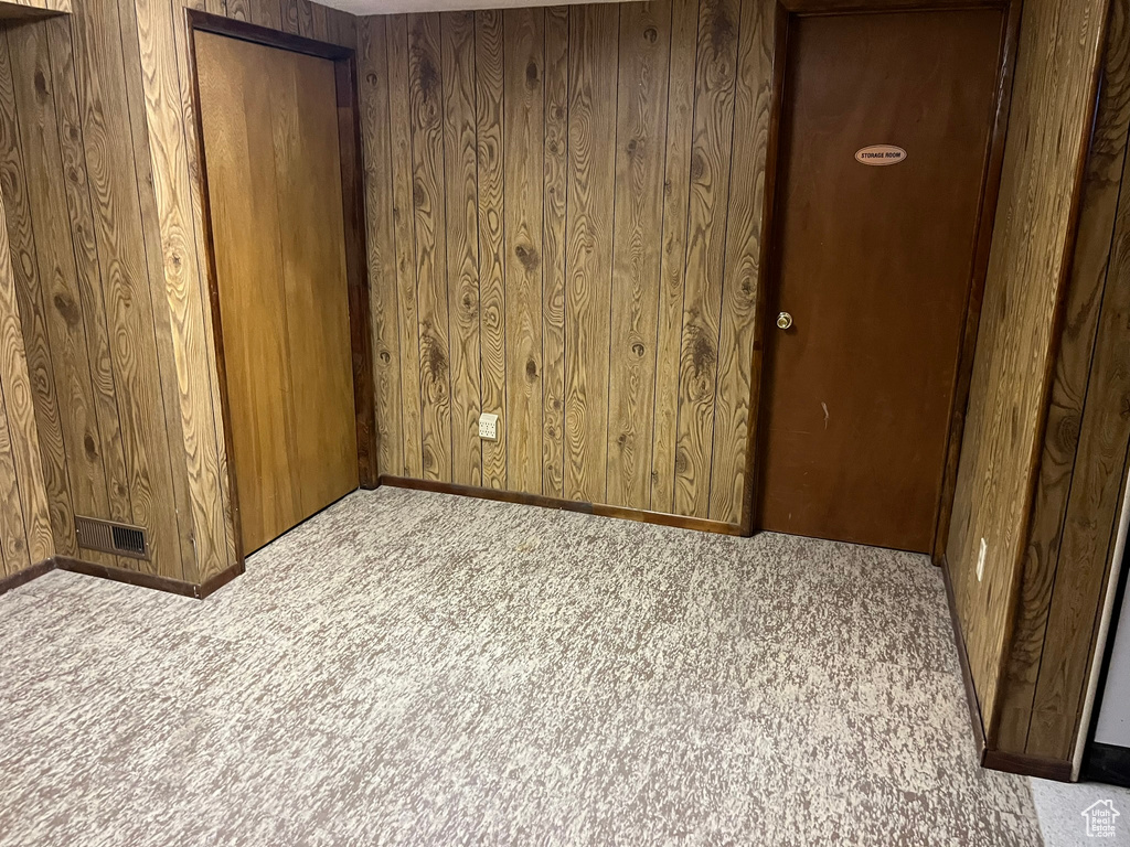 Spare room featuring light carpet and wooden walls