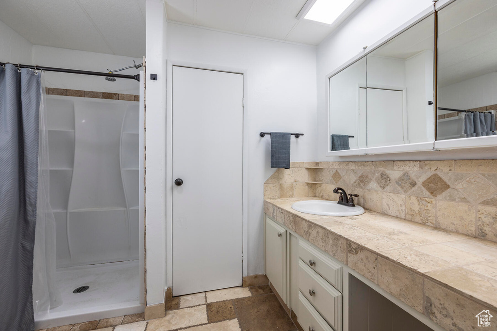 Bathroom with vanity, a shower with curtain, tasteful backsplash, and tile flooring
