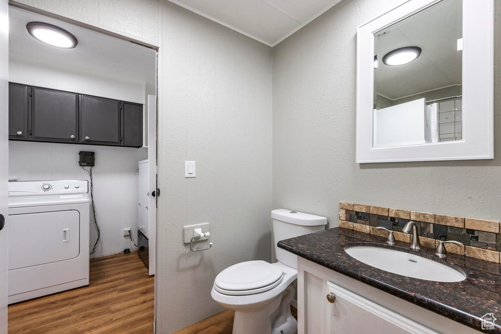 Bathroom with washer / dryer, toilet, hardwood / wood-style flooring, and vanity