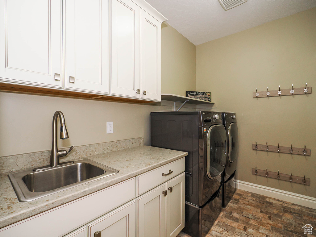 Laundry room featuring independent washer and dryer, sink, and cabinets