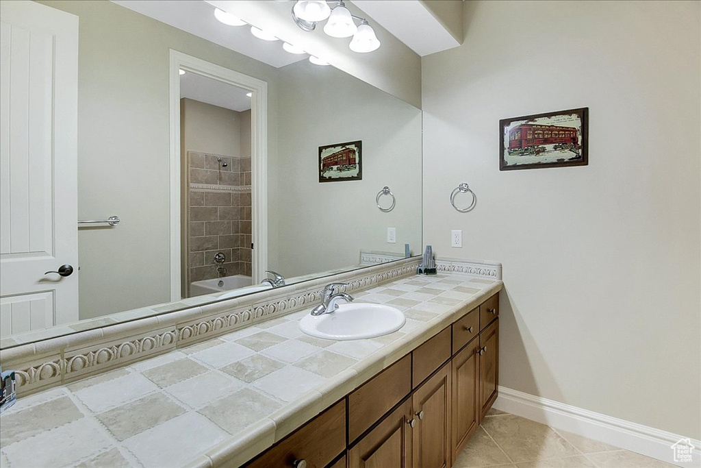 Bathroom with tile flooring, oversized vanity, and tiled shower / bath combo