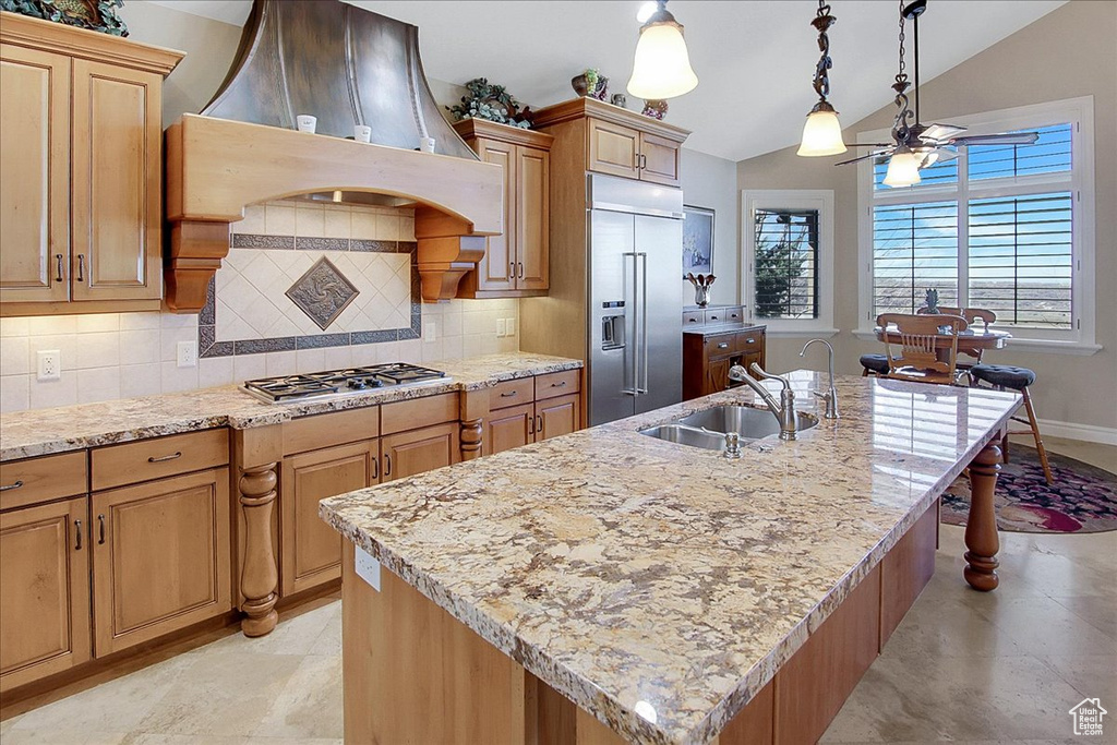 Kitchen featuring backsplash, appliances with stainless steel finishes, light tile floors, ceiling fan, and an island with sink