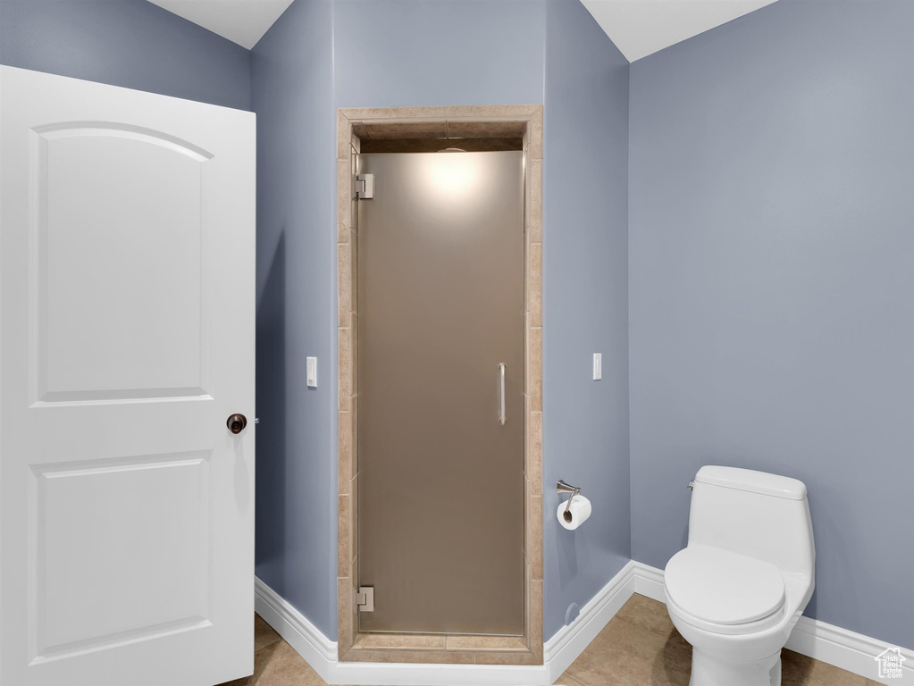 Bathroom with toilet, walk in shower, and tile floors