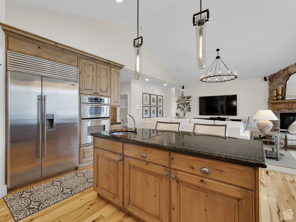 Kitchen featuring appliances with stainless steel finishes, light wood-type flooring, pendant lighting, and a chandelier
