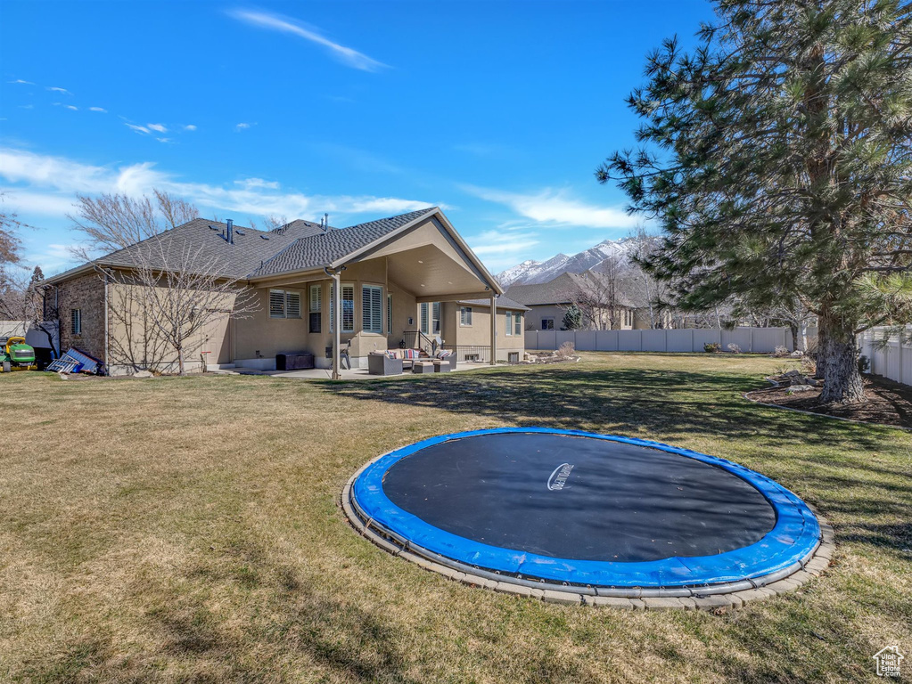 View of yard featuring a trampoline, a mountain view, and a patio