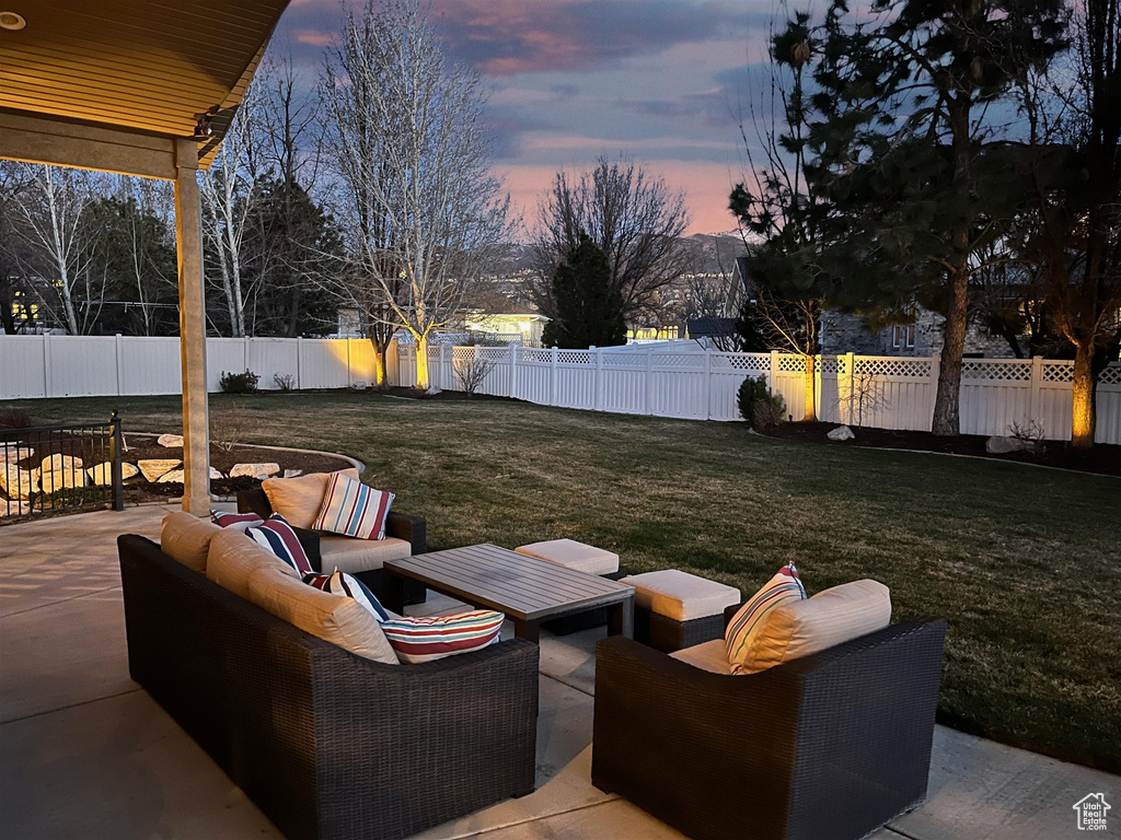 Patio terrace at dusk featuring an outdoor hangout area and a yard