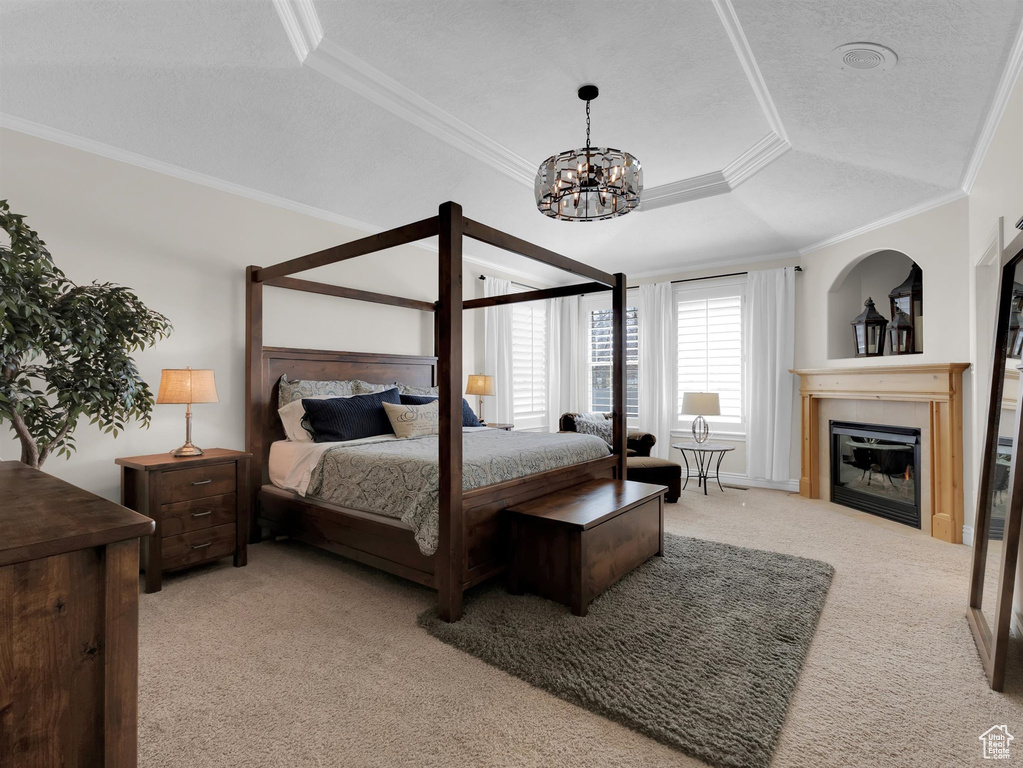Bedroom with a raised ceiling, ornamental molding, an inviting chandelier, and light colored carpet