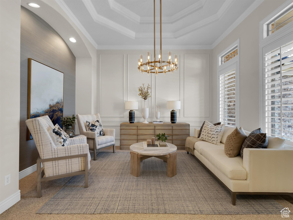 Living room featuring crown molding, a notable chandelier, and a raised ceiling