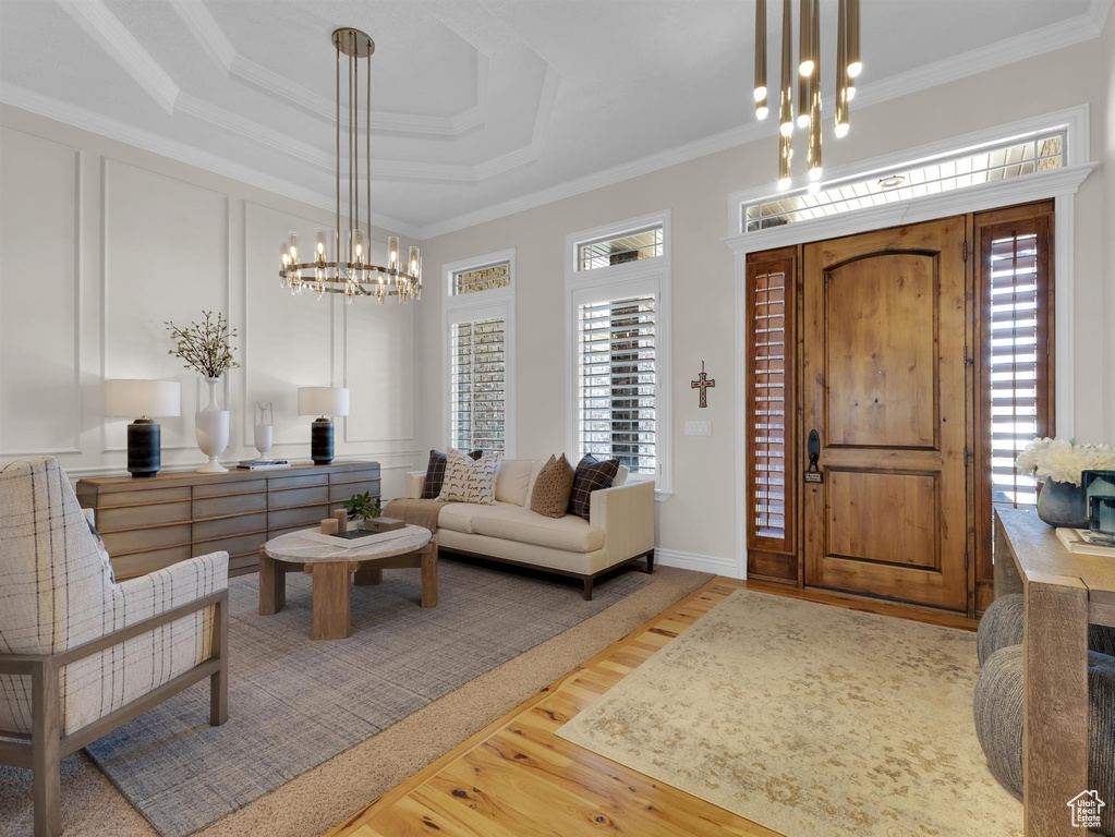 Entrance foyer featuring a wealth of natural light, an inviting chandelier, ornamental molding, and a raised ceiling