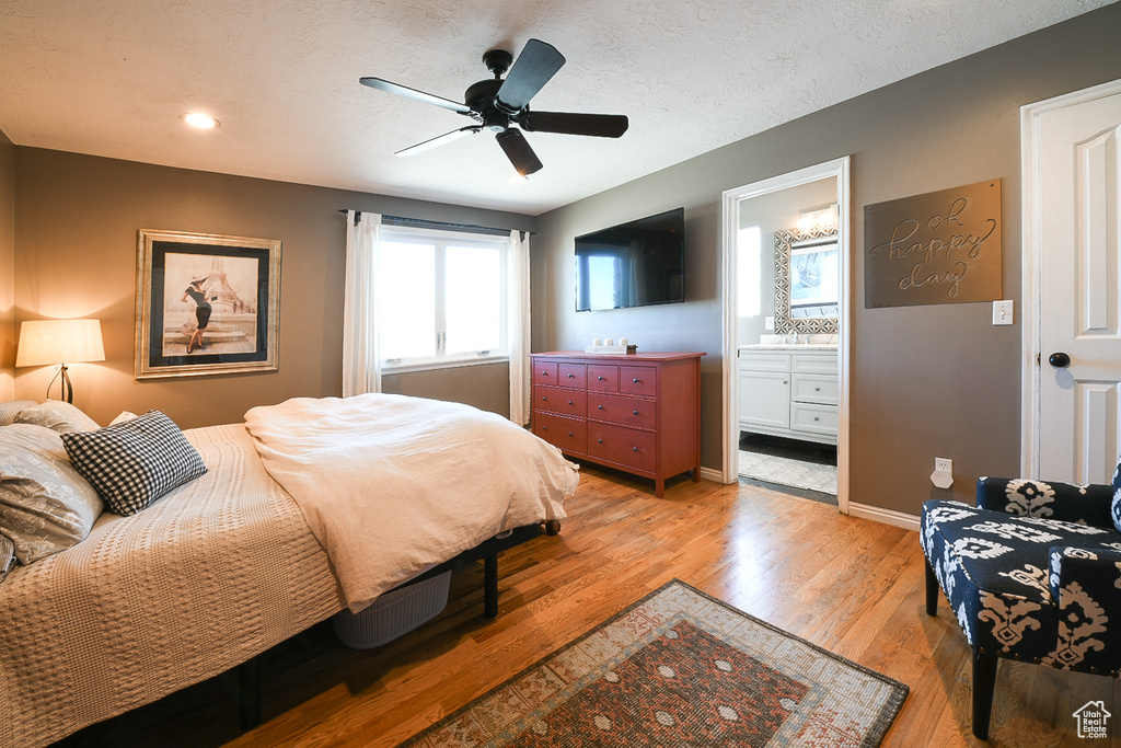 Bedroom featuring ensuite bath, light hardwood / wood-style floors, and ceiling fan