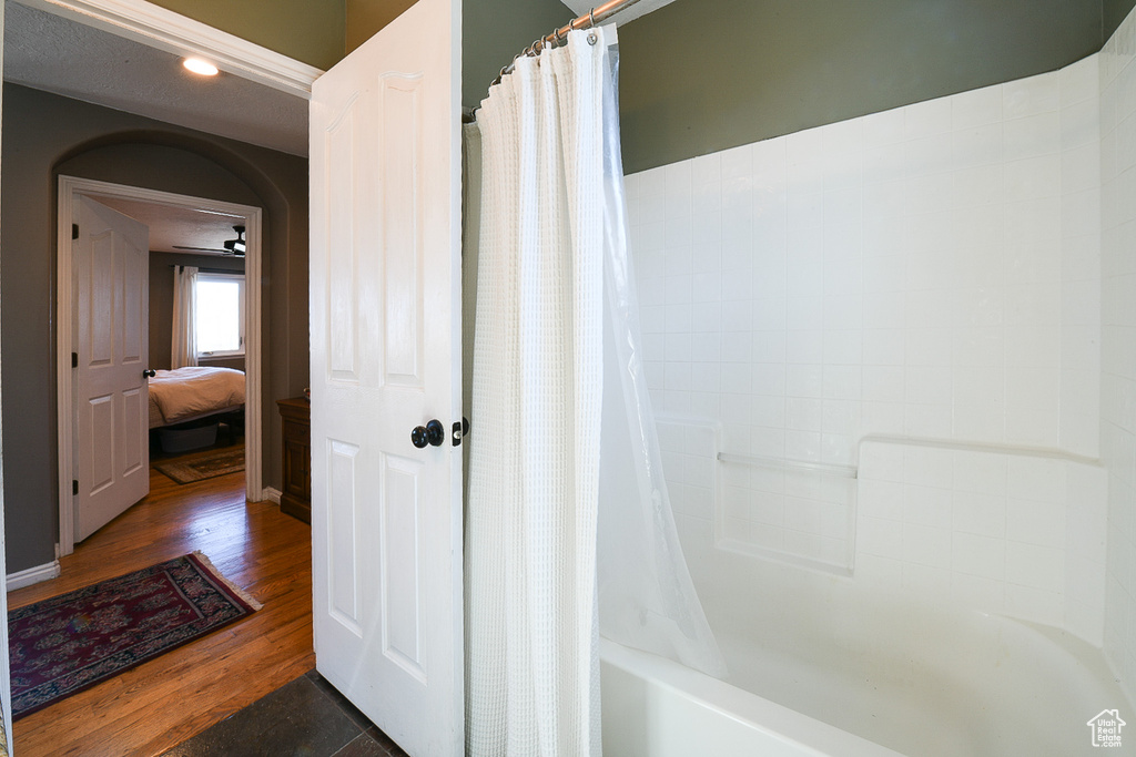 Bathroom with shower / bath combo with shower curtain, ceiling fan, and hardwood / wood-style floors