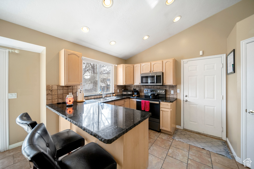 Kitchen featuring tasteful backsplash, electric range oven, light tile floors, and light brown cabinetry