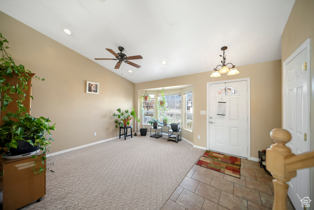 Entryway with ceiling fan with notable chandelier, lofted ceiling, and light tile floors