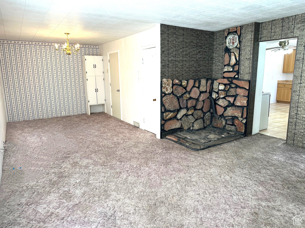 Spare room with ceiling fan with notable chandelier and light colored carpet