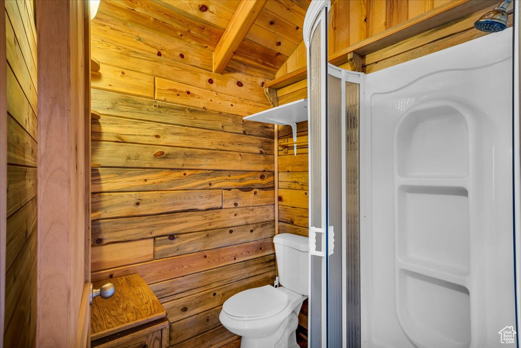 Bathroom featuring lofted ceiling, wood walls, wooden ceiling, and toilet