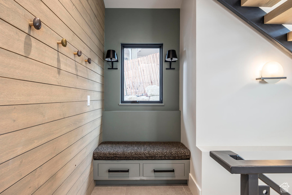 Mudroom featuring wooden walls and light tile flooring