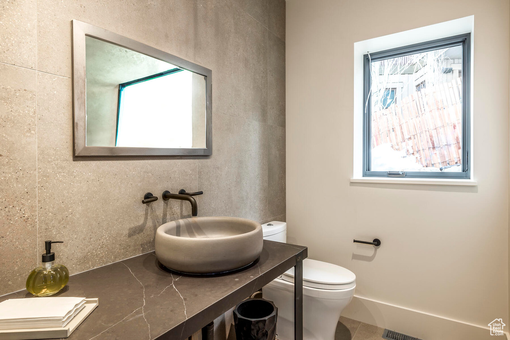 Bathroom featuring tile flooring, plenty of natural light, toilet, and vanity
