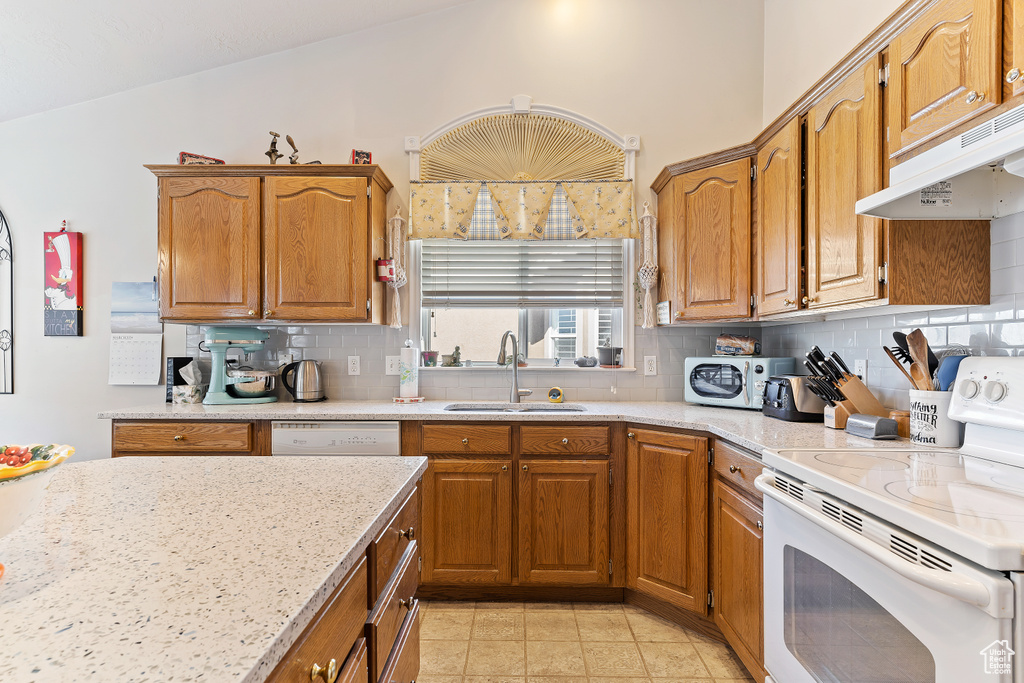 Kitchen featuring sink, white appliances, lofted ceiling, light tile floors, and backsplash