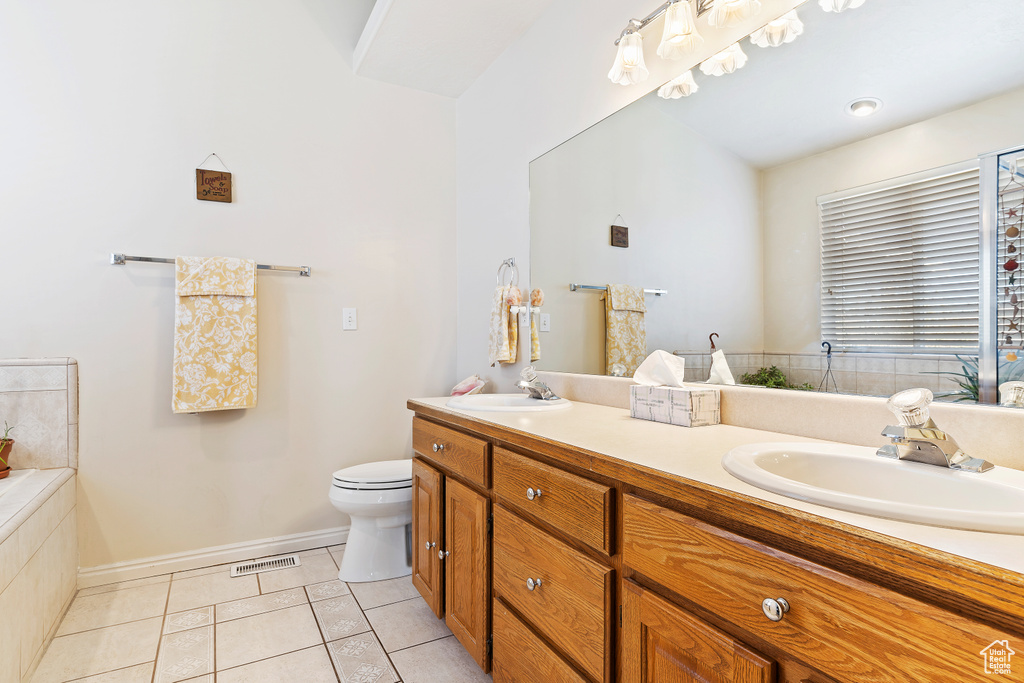 Bathroom with dual bowl vanity, toilet, and tile floors