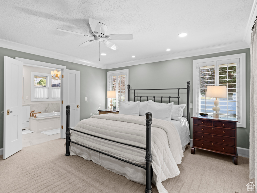Carpeted bedroom with ceiling fan with notable chandelier, ensuite bath, a textured ceiling, and crown molding