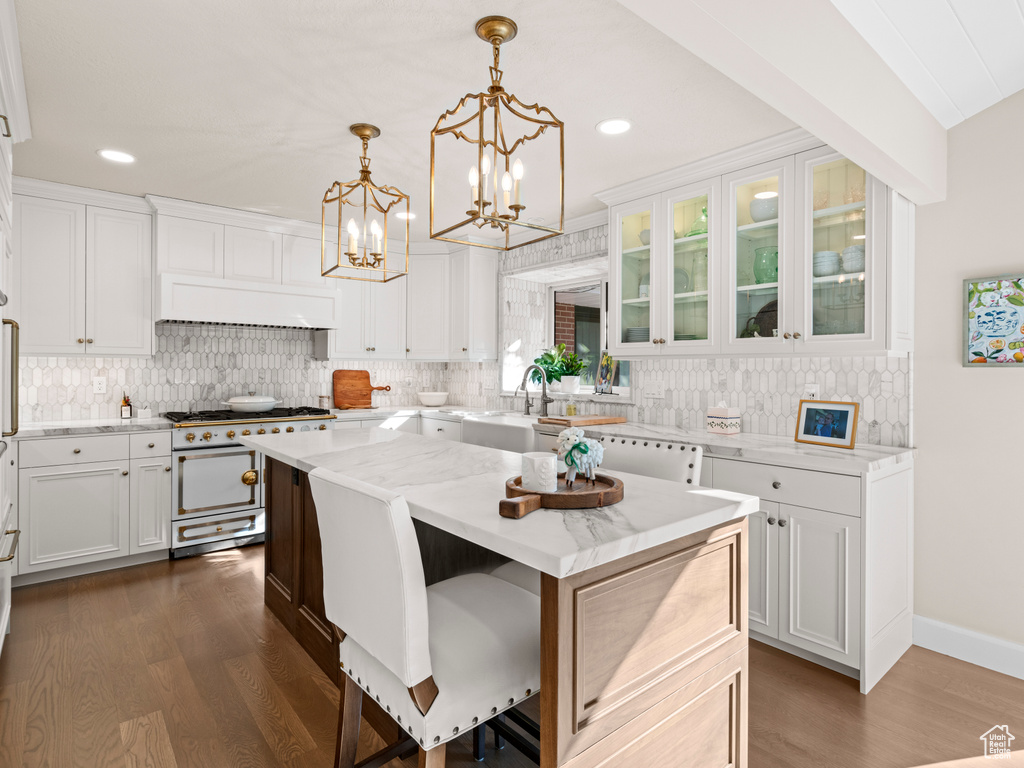 Kitchen featuring white cabinets, a kitchen island, dark hardwood / wood-style floors, and range with two ovens