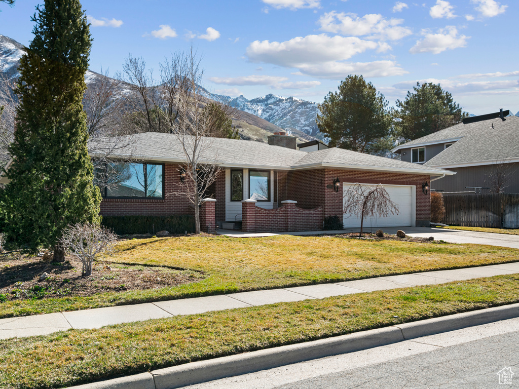 View of front of property with a mountain view, a garage, and a front lawn