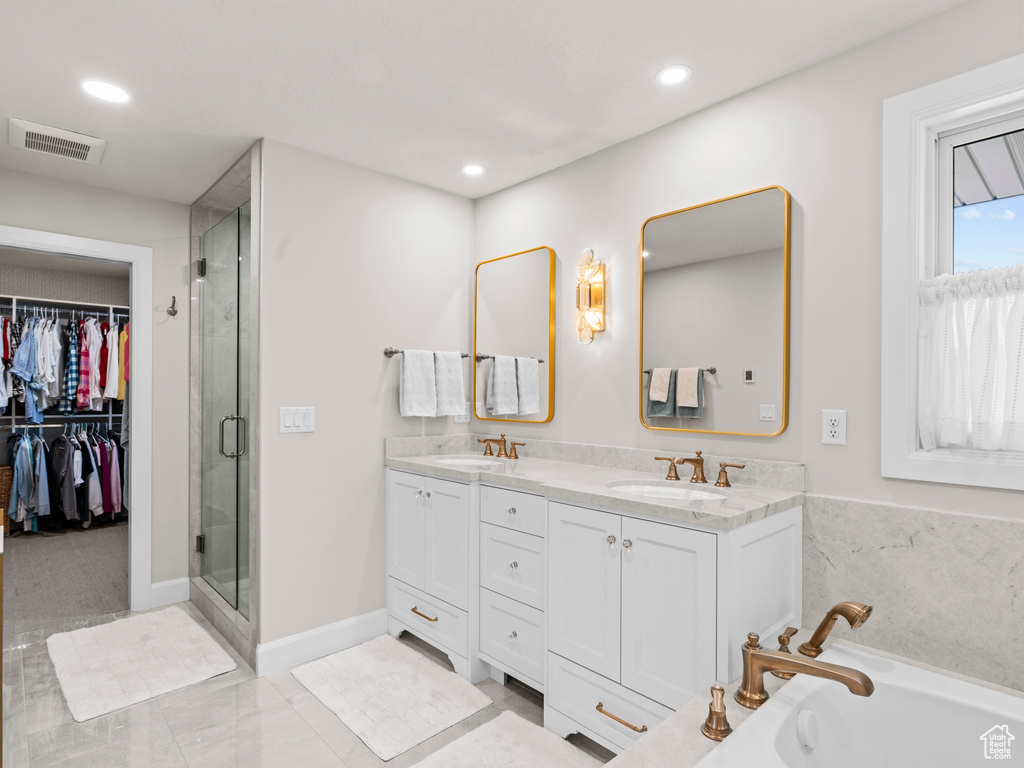 Bathroom featuring large vanity, tile floors, dual sinks, and plus walk in shower