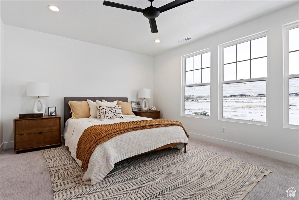 Bedroom with multiple windows, light carpet, and ceiling fan