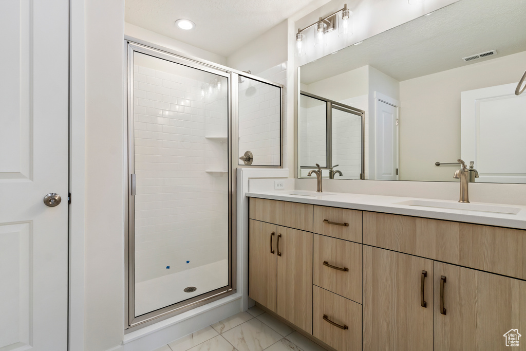 Bathroom with double vanity, tile floors, and an enclosed shower