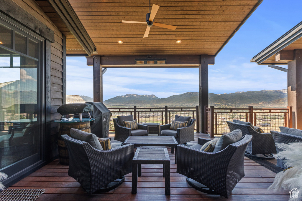 Wooden terrace featuring a mountain view, an outdoor living space, and ceiling fan