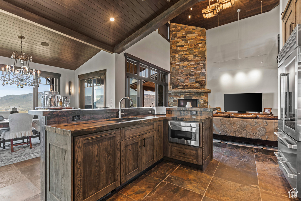 Kitchen with beamed ceiling, a chandelier, wooden ceiling, high vaulted ceiling, and sink
