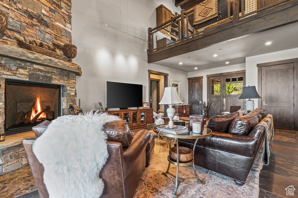Living room with a towering ceiling, a stone fireplace, and dark hardwood / wood-style flooring