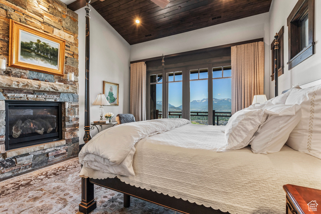 Bedroom featuring a fireplace, a mountain view, wooden ceiling, and access to outside